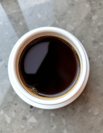 Coffee in a white cup on the table, top view