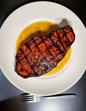 Grilled duck breast with sauce on a white plate. Top view.