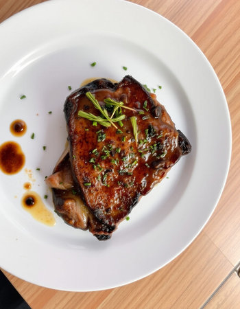 Grilled pork chop with sauce on a white plate in a restaurant