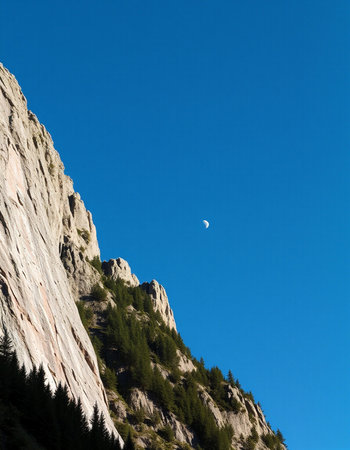 Moon in the blue sky over the alpine mountains of Dolomitesの写真素材