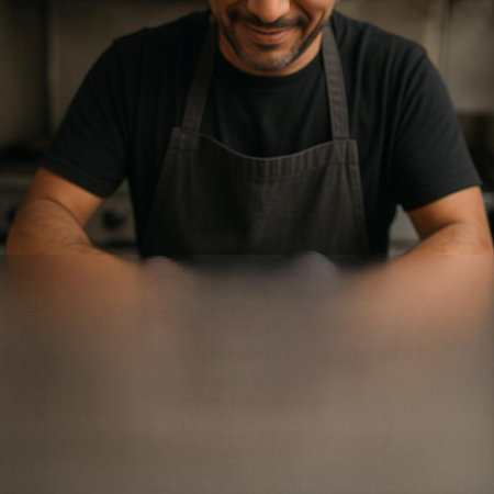 Close-up of a man in a black T-shirt and a gray apron working in the kitchen
