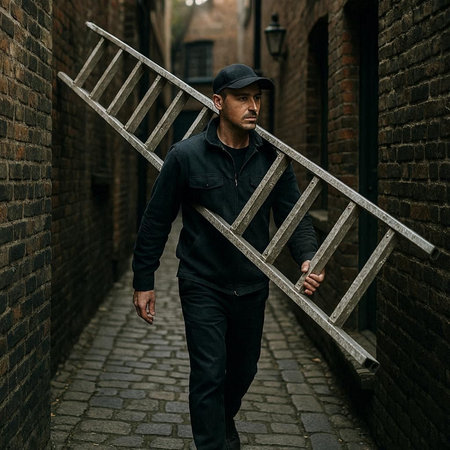 Handsome young man in a black baseball cap with a wooden ladder in the city.の写真素材