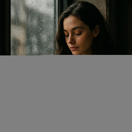 Portrait of a young beautiful woman standing near the window in the rain.の写真素材