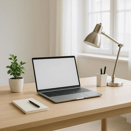 Mockup laptop with blank screen and office supplies on wooden table.