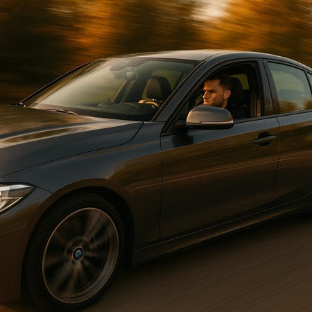 Side view of a man driving a car on a road in motion blurの写真素材