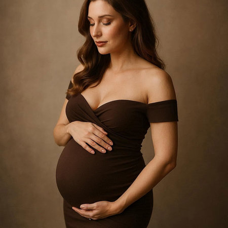 Pregnant woman in black dress touching her belly with hands.