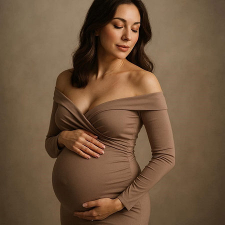 Pregnant woman in beige dress touching her belly on gray background