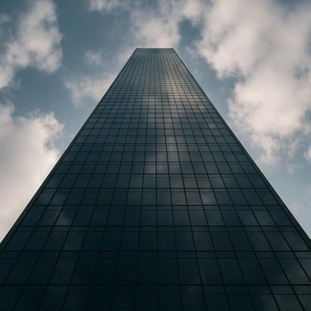 Low angle view of modern skyscraper against blue sky with clouds.