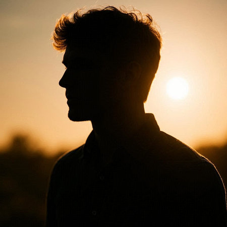 Silhouette of a young man at sunset in the rays of the setting sunの写真素材