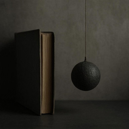 Black bomb hanging from a book on a dark background with space for text