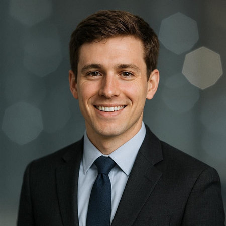 Portrait of a handsome young businessman smiling against a grey background.