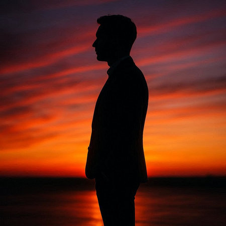 Silhouette of a man in a business suit on a sunset background