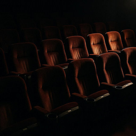 Rows of empty cinema auditorium seats in dark room with spotlight