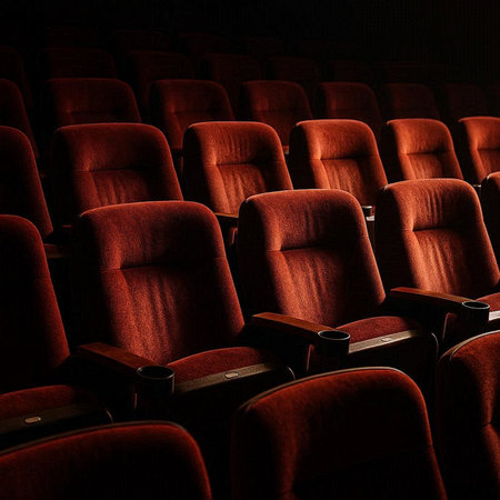 Empty cinema auditorium with rows of red seats illuminated by the spotlightの写真素材
