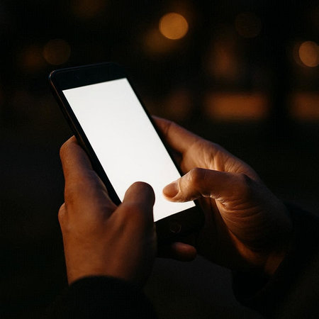 Close-up of a man using a mobile smart phone in the darkの写真素材