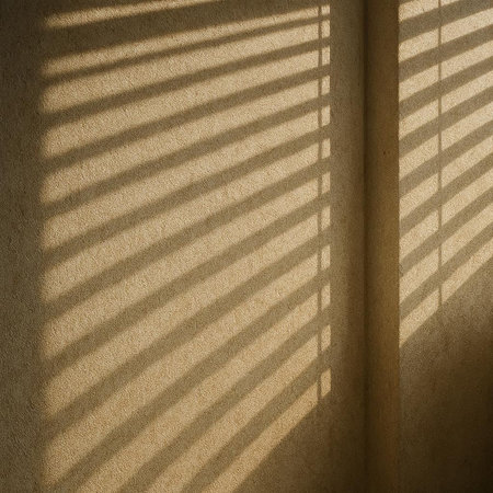 Sunlight through the blinds on the wall of a room.