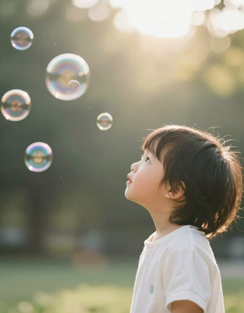 Cute asian boy playing with soap bubbles in the park.