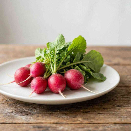 Fresh radish with green leaves on a white plate on a wooden background