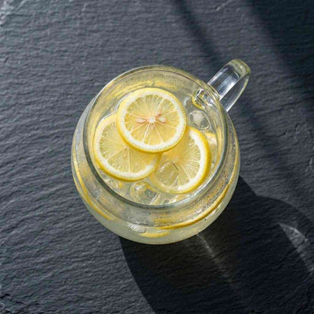 Mug of lemonade with fresh lemon slices on a black background