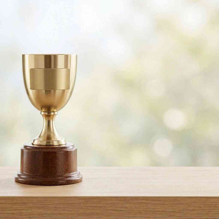 golden trophy cup on wood table with bokeh background.