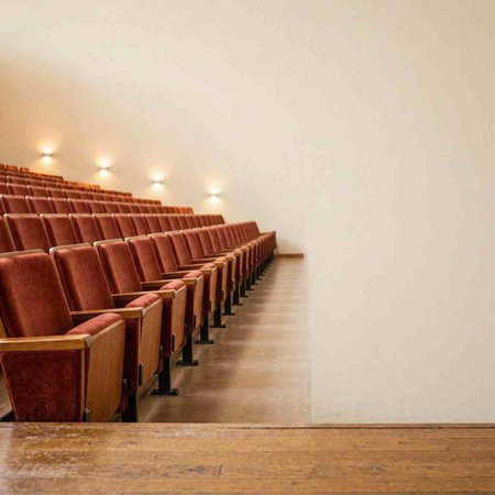 Empty cinema auditorium with row of seats and white wall in background