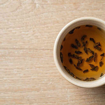 Green tea in a ceramic cup on a wooden background. Top view.
