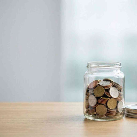 Coins in a glass jar on the table. Saving money concept.