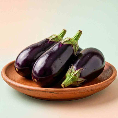 Eggplants in a clay plate on a green background.