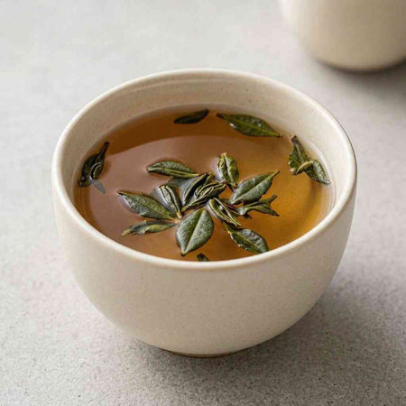 Cup of tea with green tea leaves on a gray background.