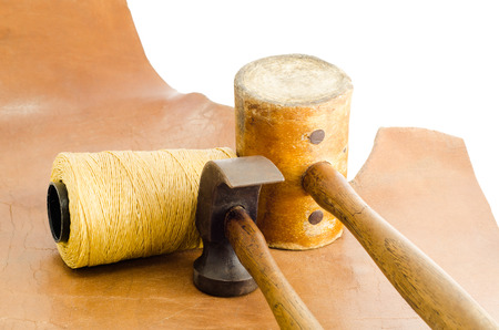 Leather hammer and hand tool for shoemaker in his workshop repairing leather shoe on white...