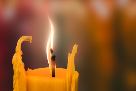 Candle in front of many defocused candleflames creating a spiritual atmosphere and in remembrance and spirituality.の写真素材