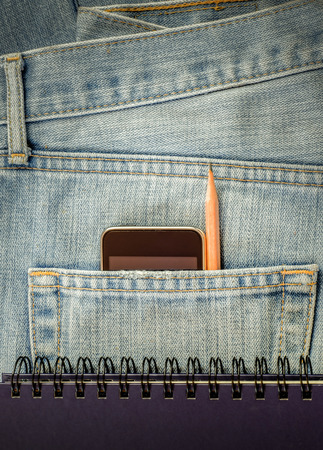 Modern phone in old blue jeans pocket.の写真素材