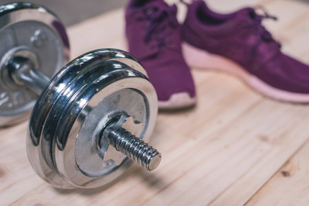purple sports shoes with dumbell on wooden floorの写真素材