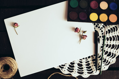 Cozy blank a4 sheet mockup, Blank paper with artist brushes on wooden table with cup and cameraの写真素材