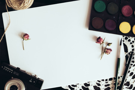 Cozy blank a4 sheet mockup, Blank paper with artist brushes on wooden table with cup and cameraの写真素材