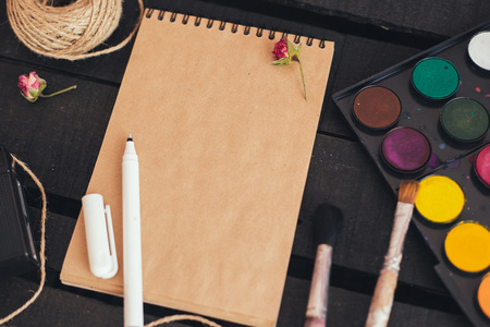 Cozy blank a4 sheet mockup, Blank paper with artist brushes on wooden table with cup and cameraの写真素材