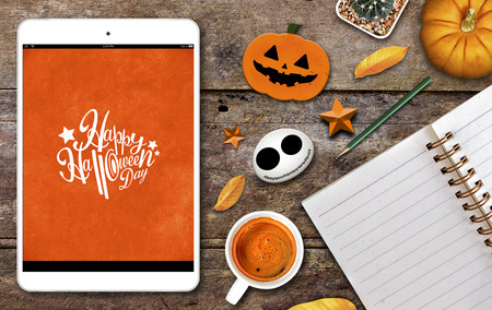 halloween concept, tablet computer, coffee cup, notebook and pumpkin on old woodeb table background, high contrastの写真素材