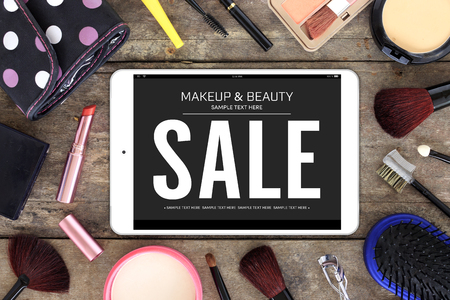 makeup cosmetics and brushes with tablet computer on wooden table background, mockup banner and over lightの写真素材