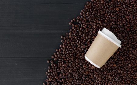 paper cup and coffee bean on black wood background. top view