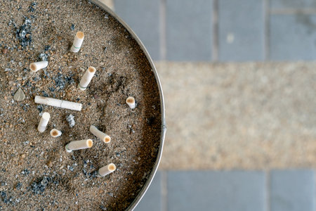 cigarettes butt in ashtray with soft-focus and over light in the backgroundの写真素材