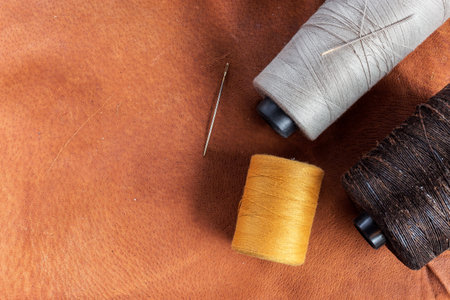 sewing accessories.  scissors, needle, thimble on leather  background, top view