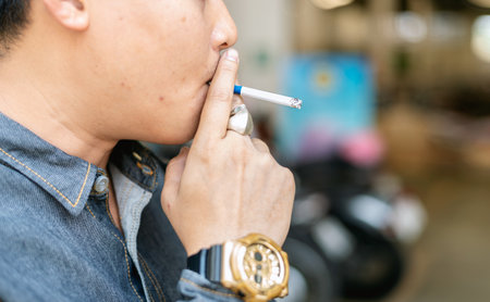 closeup young man smoking a cigarette with soft-focus and over light in the background
