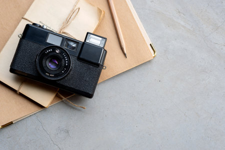 closeup vintage camera and old notebook on cement floor with soft-focus and over light in the...