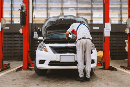 mechanic is checking the car in automobile repair service center with soft-focus and over light in the backgroundの写真素材