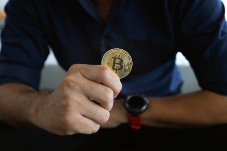 golden bitcoin in a businessman hand in the office with soft focus and backlighting. cryptocurrency...