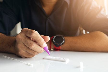 coronavirus infection prevention concept. man is holding an antigen (ATK) test kit in his hand with soft-focus and over light in the background.の写真素材