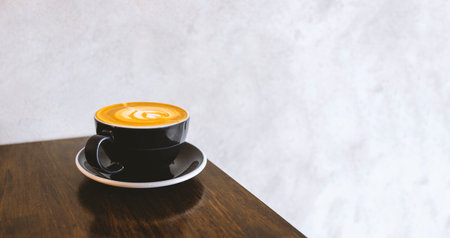 white coffee cup placed on wooden table near a bright window, capturing a serene moment of modern...