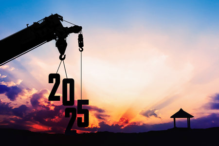 Silhouette of a crane lifting the numbers 2025 at sunset, symbolizing progress, construction, and the arrival of the new year with hope and innovationの写真素材