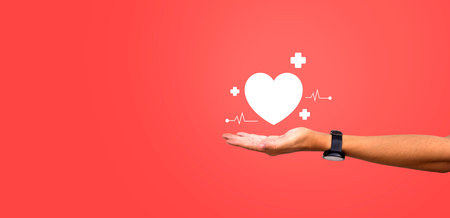 Open hand holding a heart symbol with medical icons on a red background, representing healthcare,...