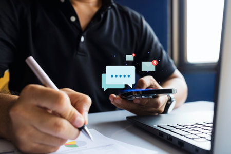 Close-up of a man multitasking with smartphone and documents, surrounded by email and task notifications, symbolizing productivity and communication.の写真素材